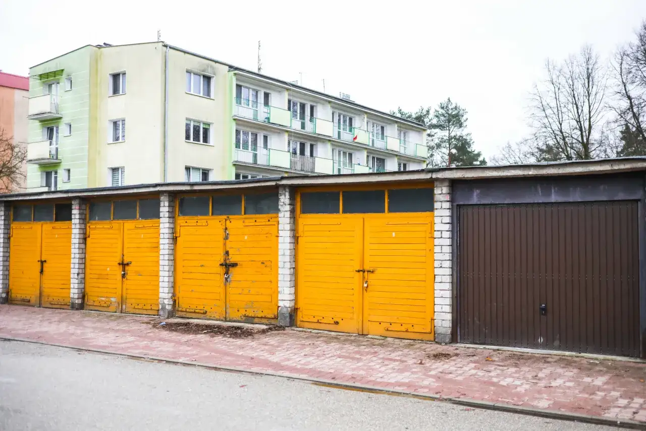 Rząd żółtych garaży i jeden brązowy przed blokiem mieszkalnym. Czy warto inwestować w garaże i miejsca postojowe przy obecnych cenach najmu?