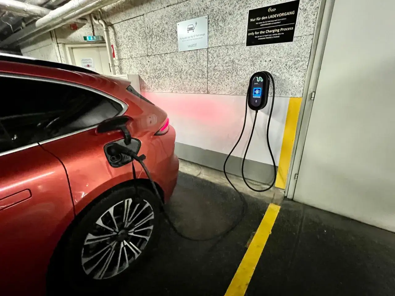 Pomarańczowy samochód elektryczny ładuje się w podziemnym garażu. Czy parkingi podziemne w blokach są bezpieczne dla samochodów elektrycznych w 2026?