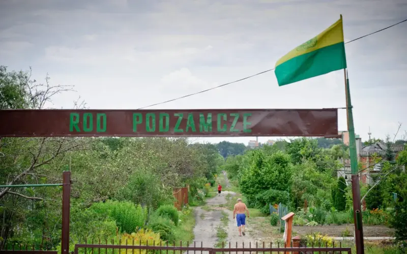 Kto stoi za kampanią "wolne działki ROD"? Czy protesty zablokują nowe przepisy? Wjazd do ROD Podzamcze, gdzie widać mężczyznę idącego ścieżką.